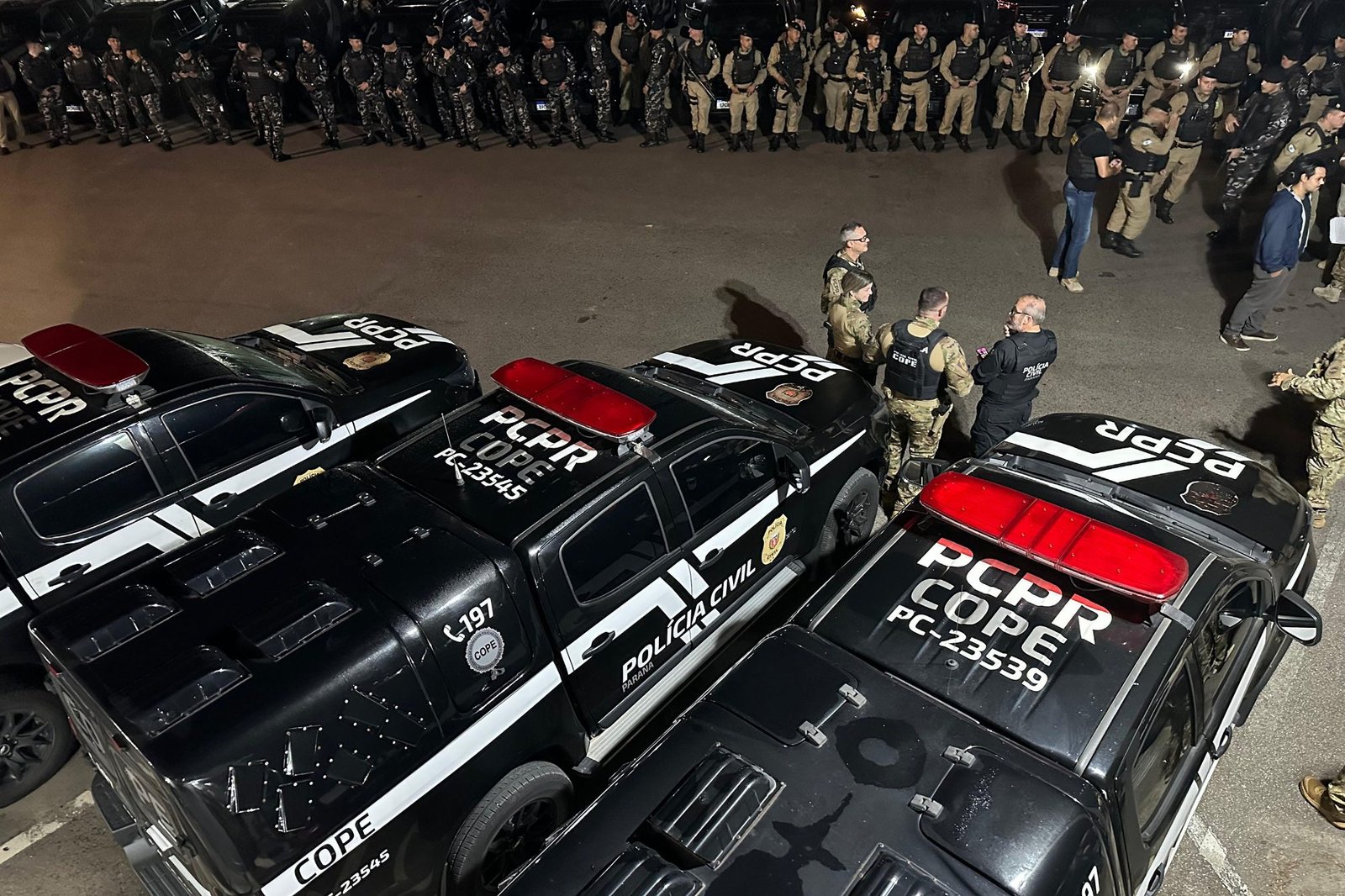 Viaturas da Polícia Civil do Paraná enfileiradas à noite antes de uma operação